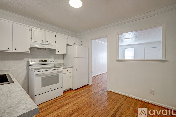 A kitchen with white appliances and wooden floors.