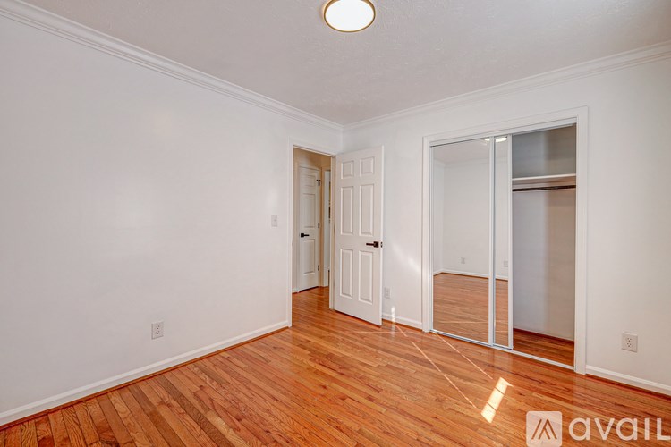 A room with a wooden floor and white walls, with a door and a window.