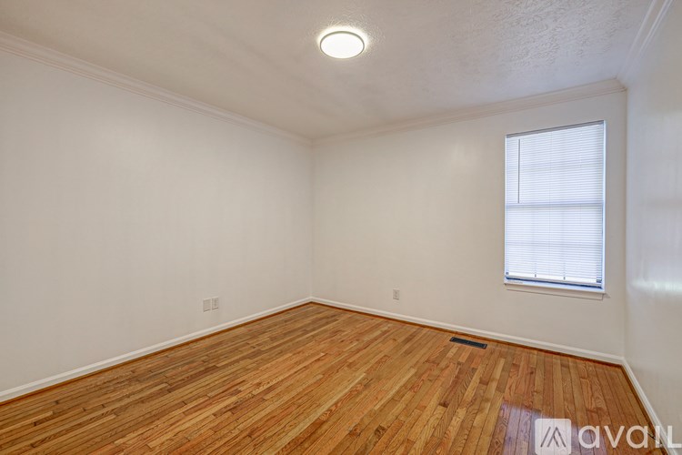 A room with wooden flooring and a window with blinds.