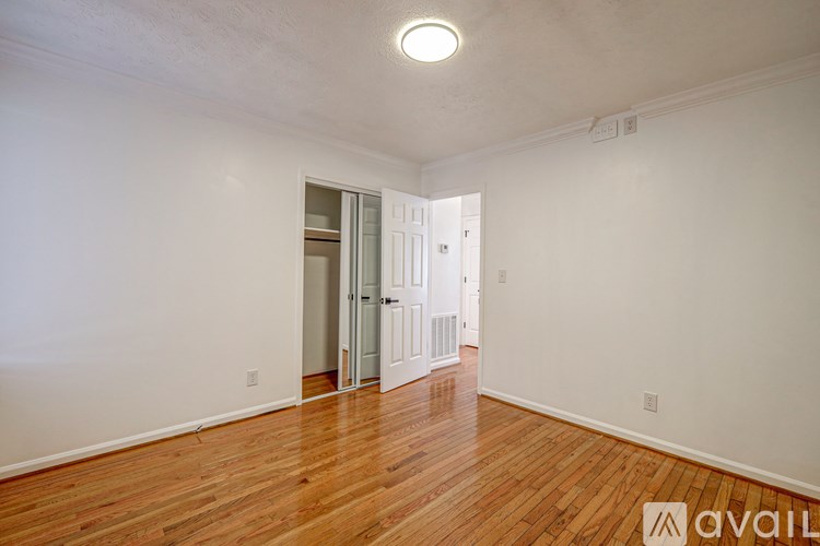 A room with wooden floors and white walls, with a doorway leading to another room.