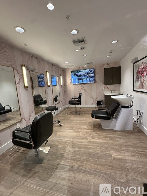 A salon with black chairs and a pink wall.