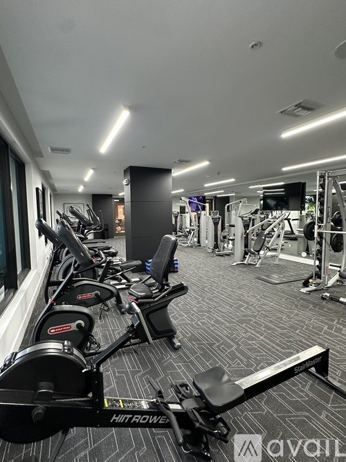A gym with a row of stationary bikes and a squat rack.