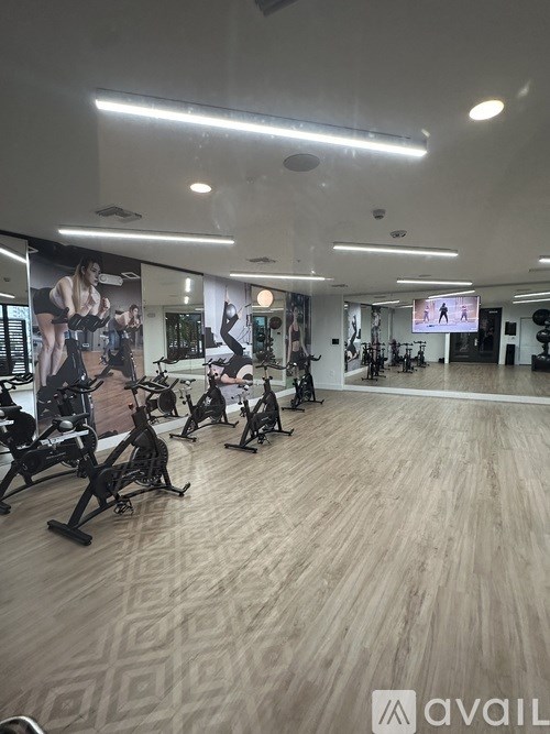 A gym with exercise bikes and a TV screen showing a workout.