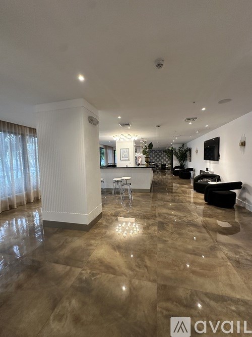 A spacious living room with a polished floor and a television mounted on the wall.