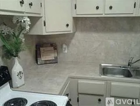 A kitchen with a white stove top oven and a white sink.