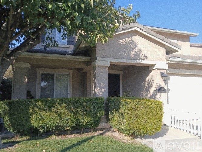 A house with a white picket fence and green bushes in front.