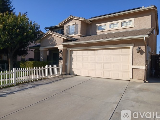 A house with a white garage door and a white picket fence.