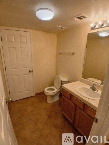 A bathroom with a toilet, sink, and mirror.