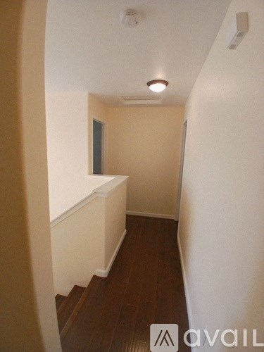 A hallway with a white wall and wooden floors.