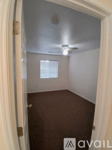 A small room with a ceiling fan and a window with blinds.