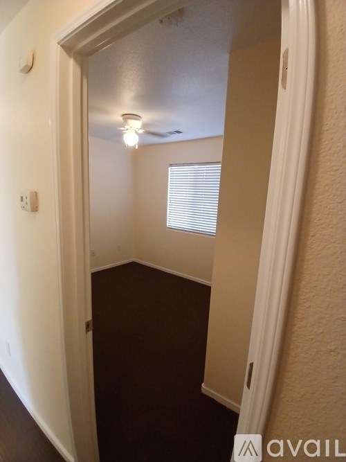 A hallway with a light on the ceiling and a window with blinds.