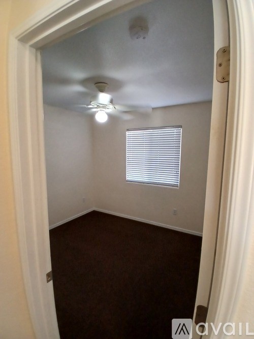 A room with a ceiling fan and a window with blinds.