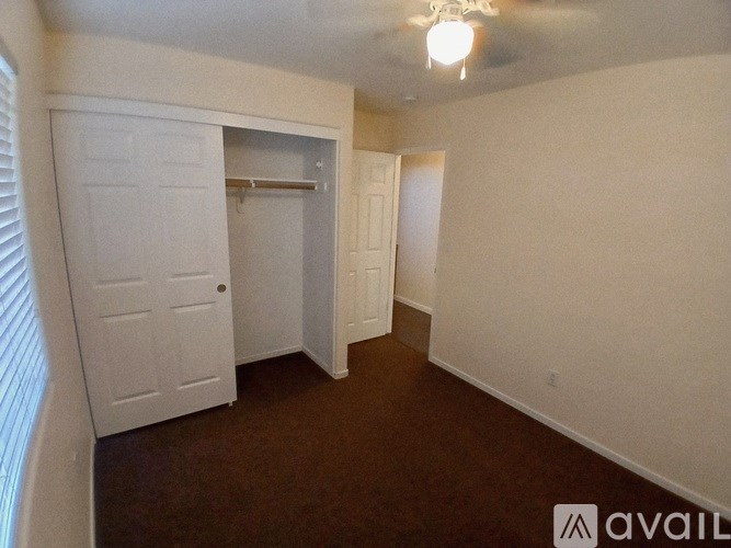 A room with a white door and a brown carpet.