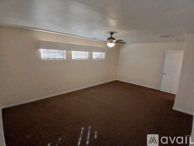 A room with brown carpet and a ceiling fan.
