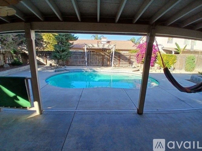 A hammock is suspended in a covered patio area overlooking a small pool.
