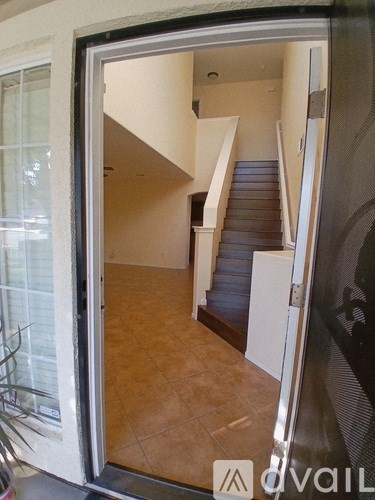 A hallway with a staircase and a doorway leading to another room.