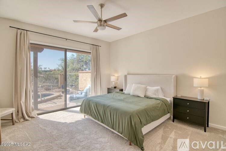 A bedroom with a large bed, a ceiling fan, and sliding glass doors.