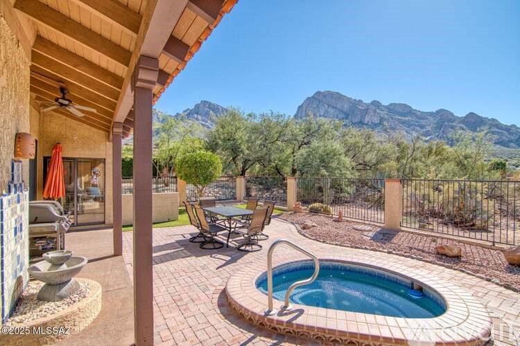 A pool with a table and chairs is surrounded by a fence.