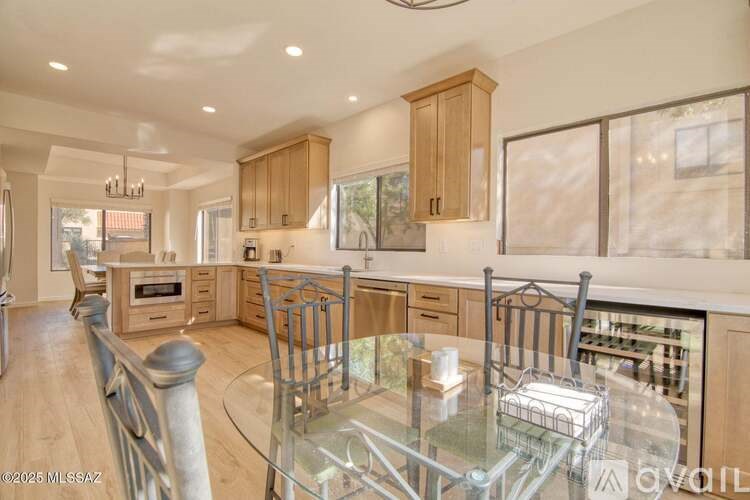 A modern kitchen with wooden cabinets and a glass dining table.