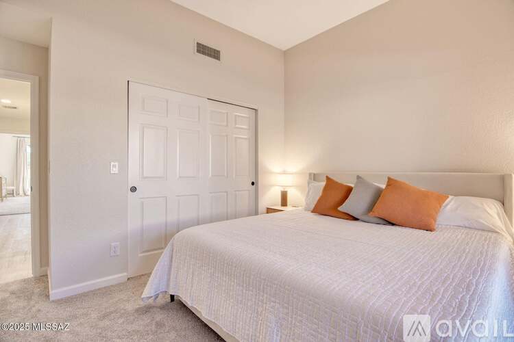 A bedroom with a bed, pillows, and a lamp.