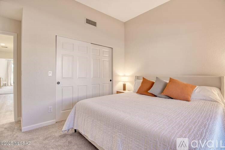 A bedroom with a bed, pillows, and a lamp.