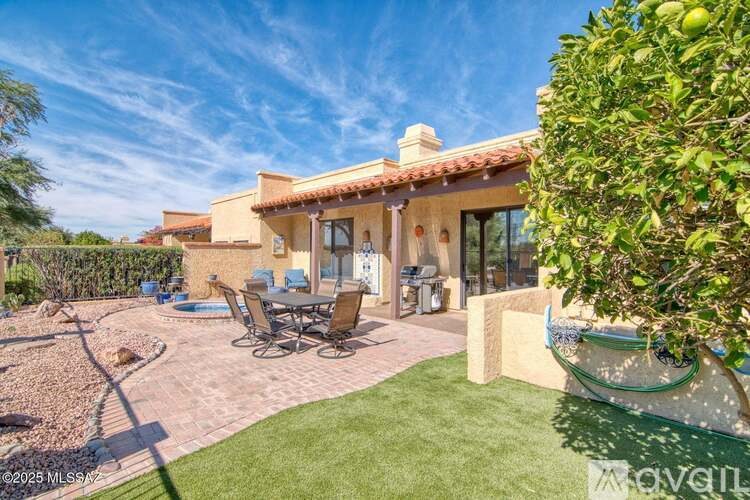 A house with a patio and a tree in front.