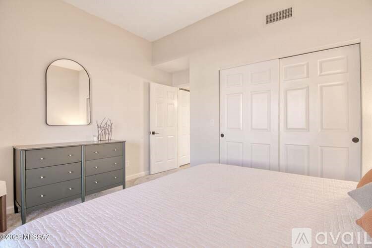 A bedroom with a large bed, a dresser, and a mirror.