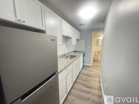 A kitchen with white cabinets and a stainless steel refrigerator.