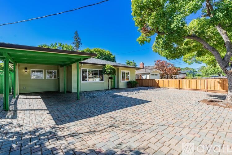 A house with a green roof and a driveway made of cobblestones.
