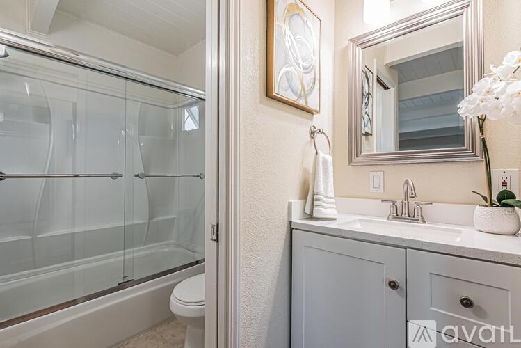 A bathroom with a glass shower door and a white sink vanity.