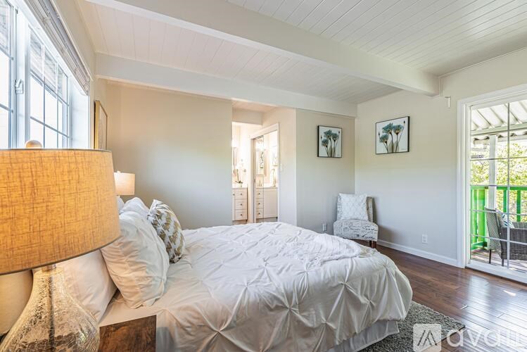 A bedroom with a large bed and a lamp.