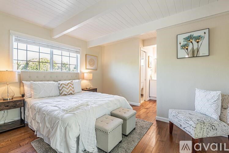 A bedroom with a large bed and a painting on the wall.