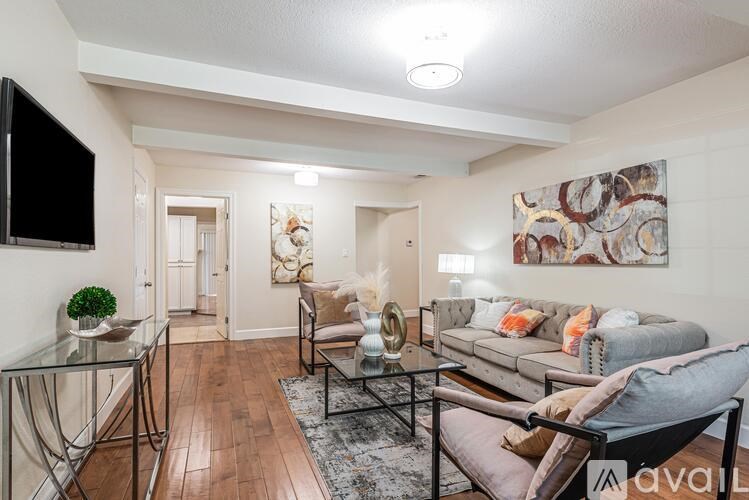 A living room with a glass table and a grey couch.