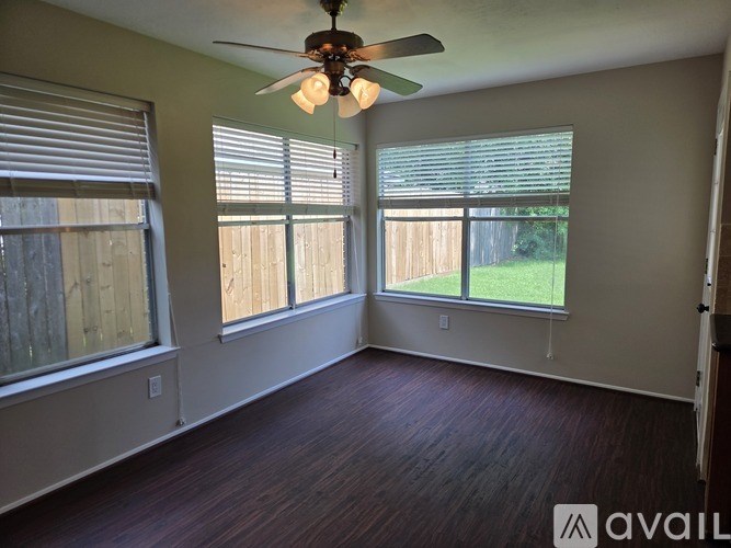A room with a ceiling fan and two windows.