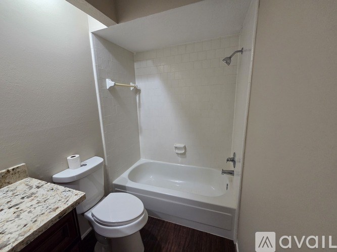 A white toilet sits next to a white bathtub in a small bathroom.