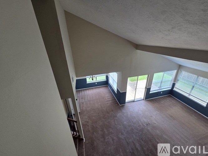A room with a wooden floor and a staircase leading to the upper floor.