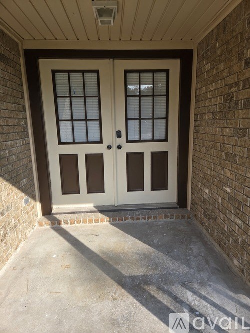 A double door with a glass panel and sidelights is set in a brick wall.