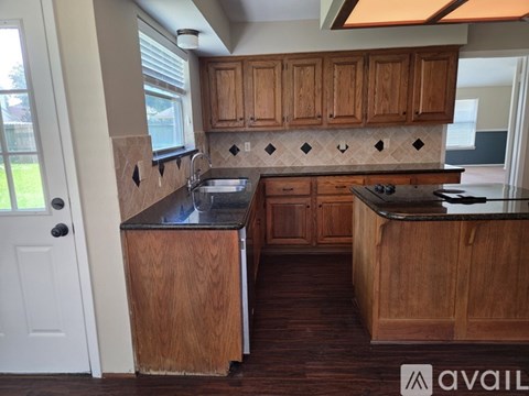 A kitchen with wooden cabinets and a black countertop.