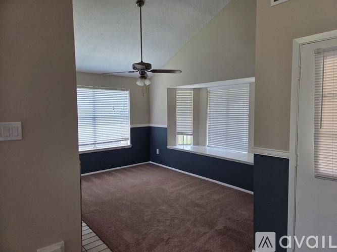 A room with a ceiling fan and windows with blinds.