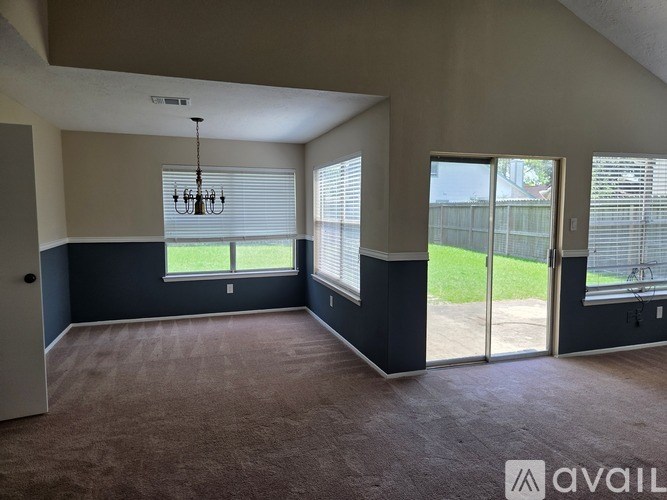 A room with a carpeted floor and a chandelier hanging from the ceiling.