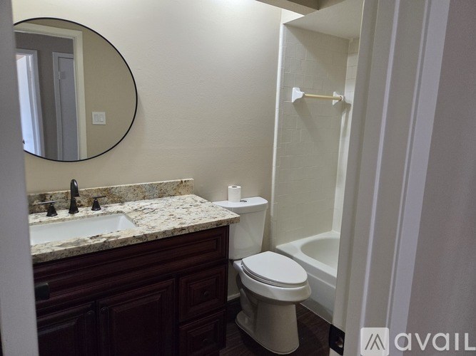 A bathroom with a toilet, sink, and mirror.