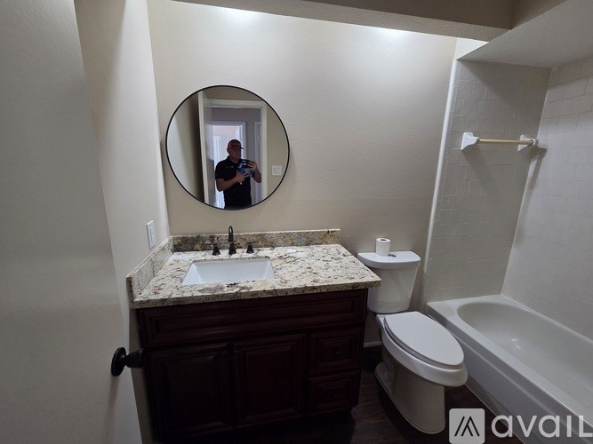 A bathroom with a marble countertop, a toilet, a sink, and a mirror.