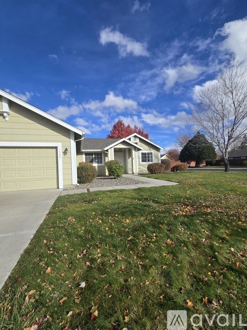 A house with a garage and a driveway with fallen leaves.