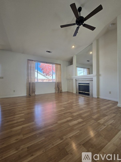 A spacious room with wooden flooring and a ceiling fan.