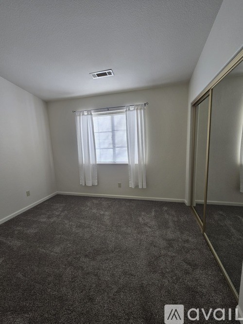 A room with a carpeted floor and a window with curtains.