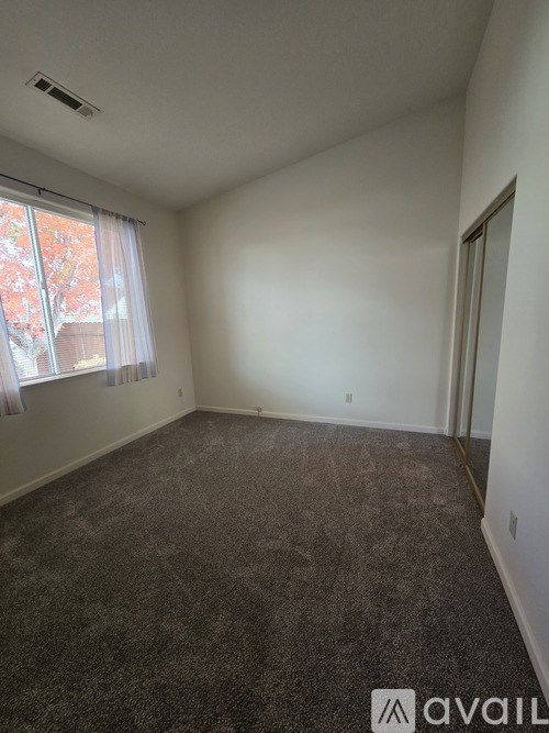 A room with a carpeted floor and a window with curtains.