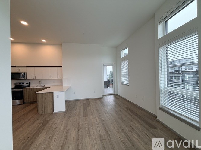 A spacious kitchen with wooden floors and white walls.
