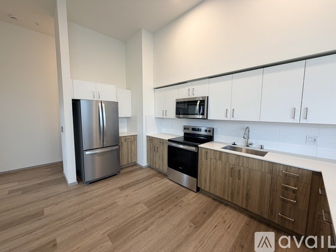 A kitchen with a refrigerator, microwave, oven, and sink.
