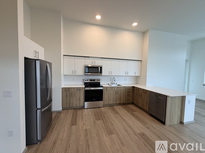 A kitchen with a refrigerator, microwave, oven, and sink.