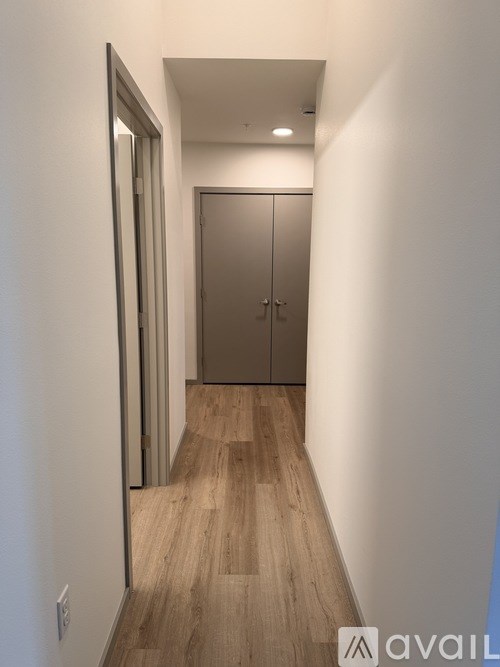 A hallway with a wooden floor and a metal door.